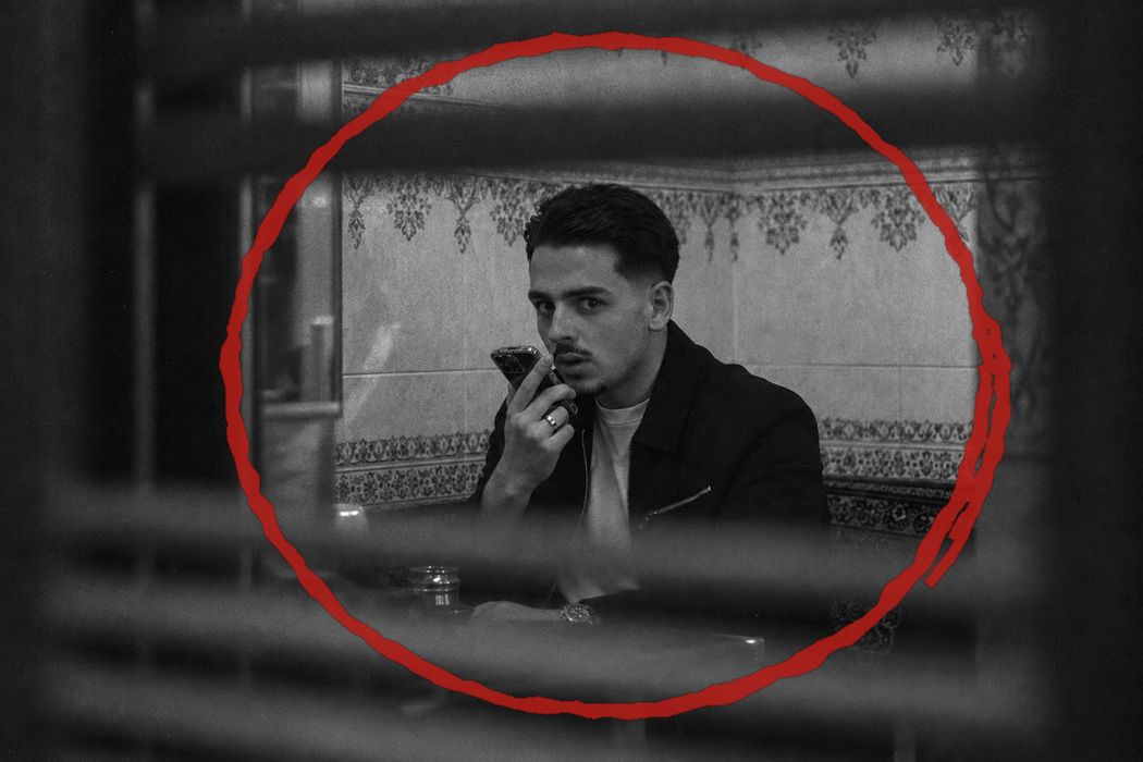 Eliezer al teléfono mirando a cámara a través de una persiana, marcado con un círculo rojo